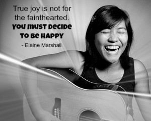 A girl playing her guitar and smiling very big with a quote about happiness from Elaine Marshall.